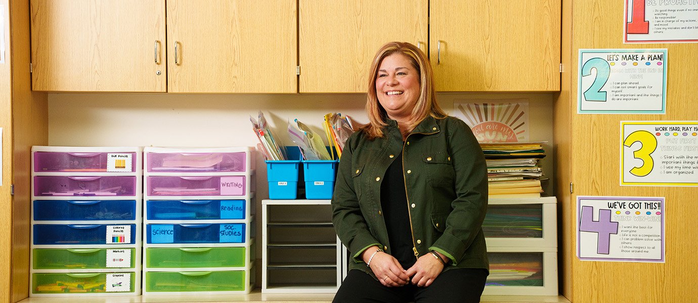 A teacher sitting on a counter in their room