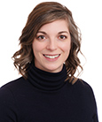 Woman with light brown hair wearing a black turtleneck smiling at the camera.