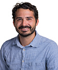 Headshot: Bearded man in Blue shirt smiling at the camera.