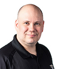 Headshot: Man in black shirt smiling at the camera.