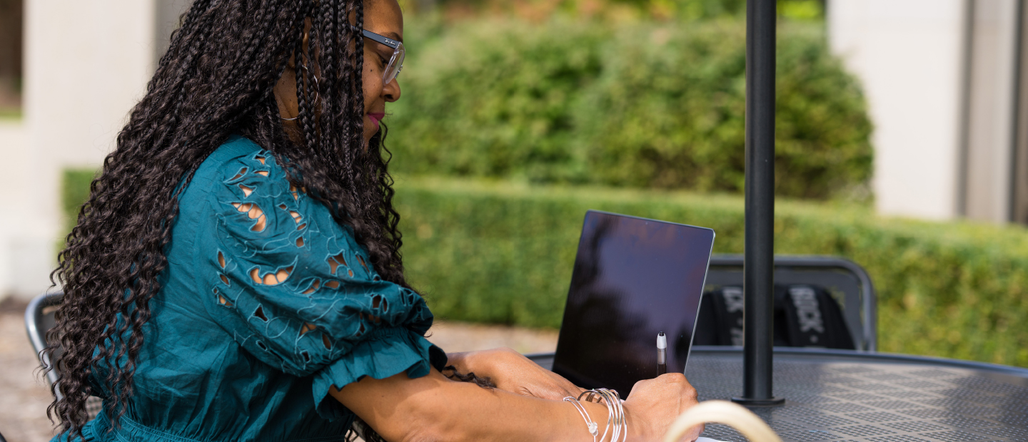 Woman typing on a laptop outside the Oakland Center