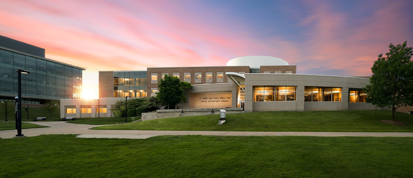 Elliott Hall on Oakland University's campus with the sun rising behind it.