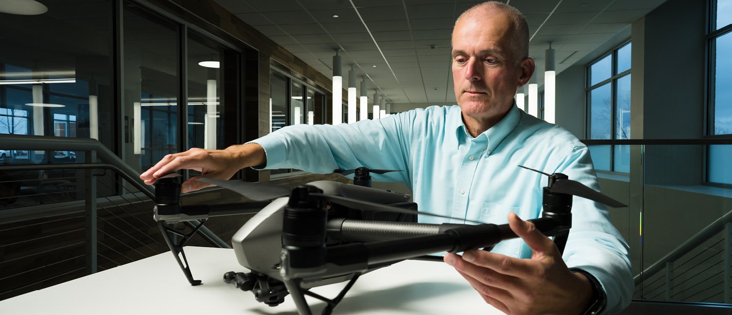 A man seated at a table, holding a drone.