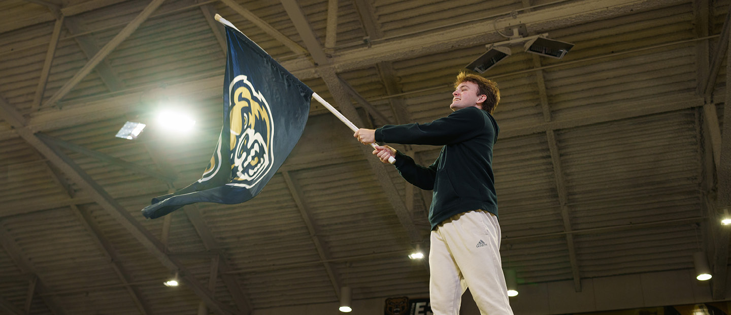 Sports Management Minor A young man waving an Oakland University flag
