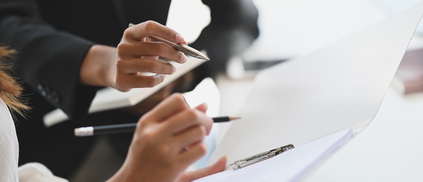 Closeup of hands holding pens and paper.