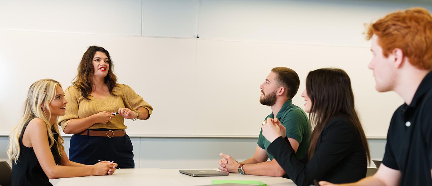 A professor standing in front of a table of students