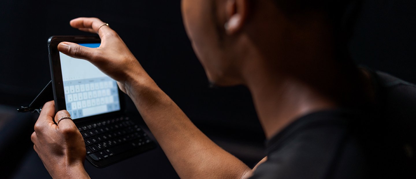 A person typing on a small tablet.