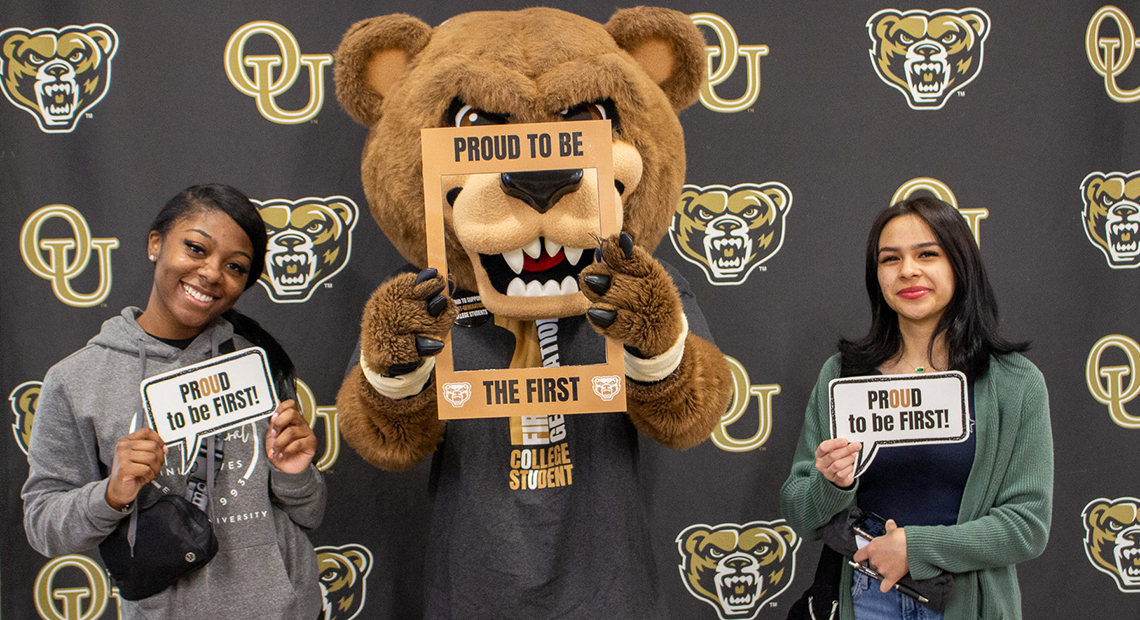 Two first generation college students posing with the Grizz mascot
