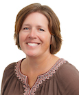 Woman with short brown hair smiling and looking at the camera.