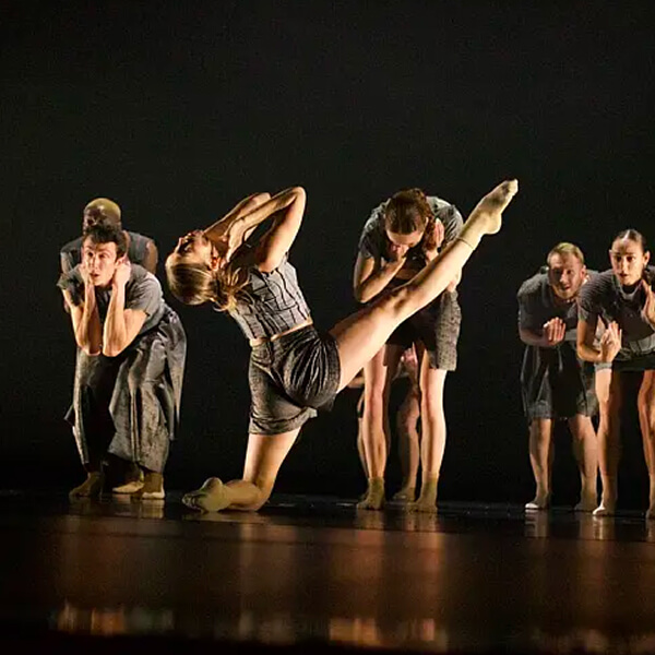 A group of male and female dancers on a stage in the spotlight.