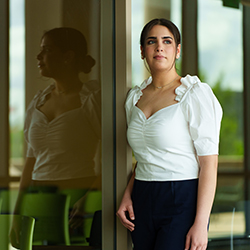A woman leaning on a window with her reflection next to her