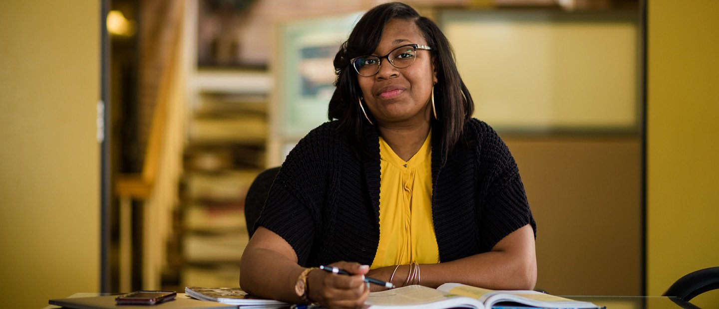 Academic Programs Banner Woman seated at a table with a pen and an open book