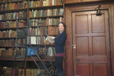 Megan Peiser standing next to a large bookshelf