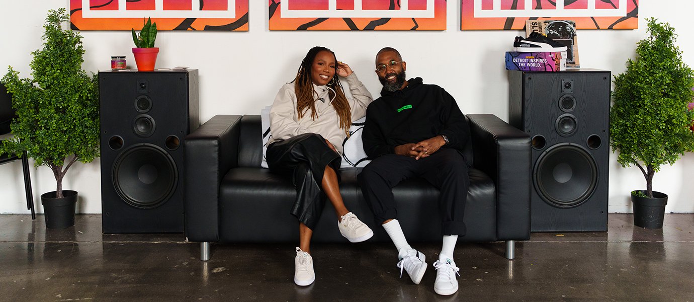 Two people sitting on a couch with speakers on either side