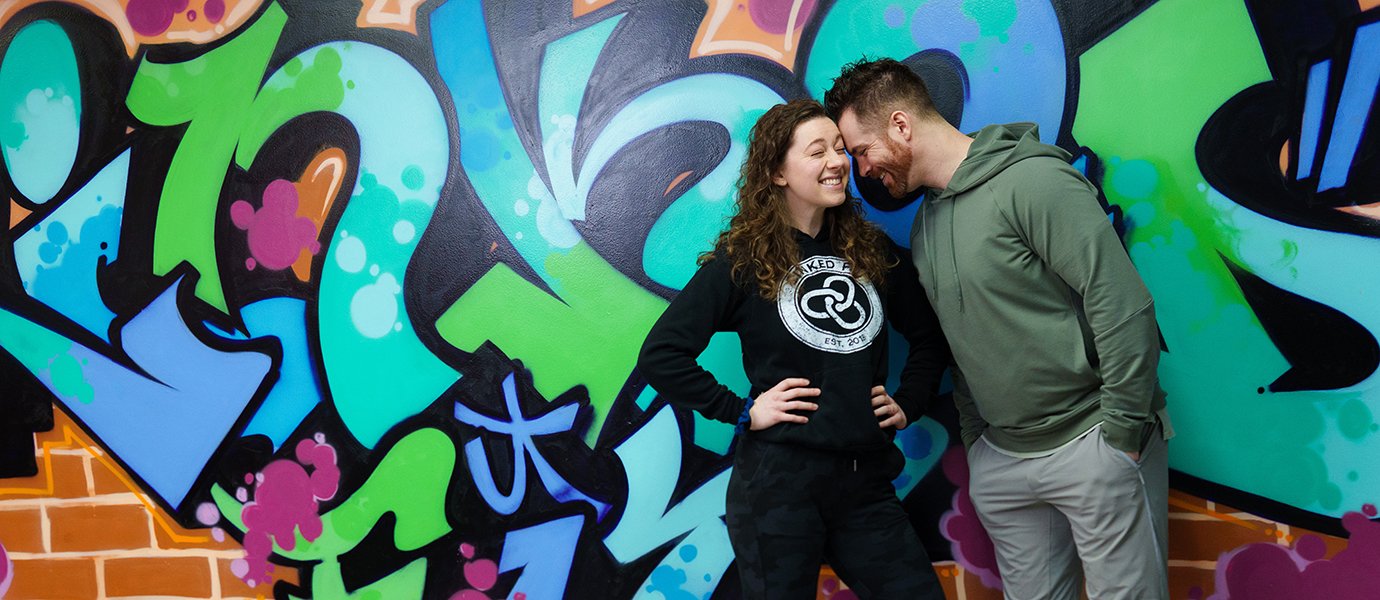 Two people next to a wall of graffiti