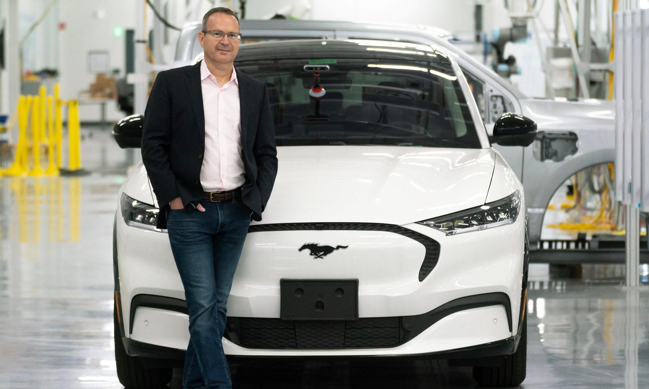 A man standing in front of a car in a factory