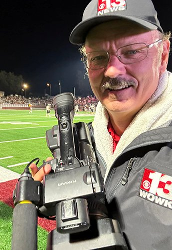 Person on a football field holding a camera