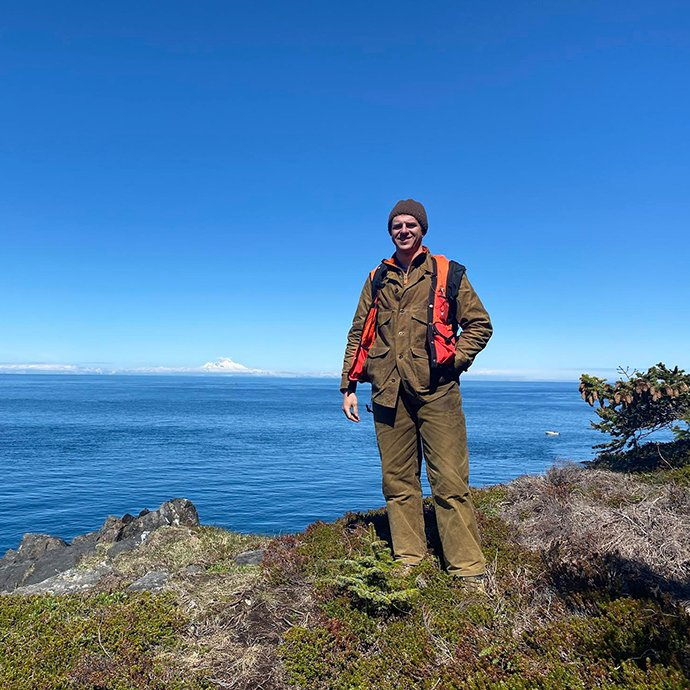 Person standing near a ledge with a body of water behind them