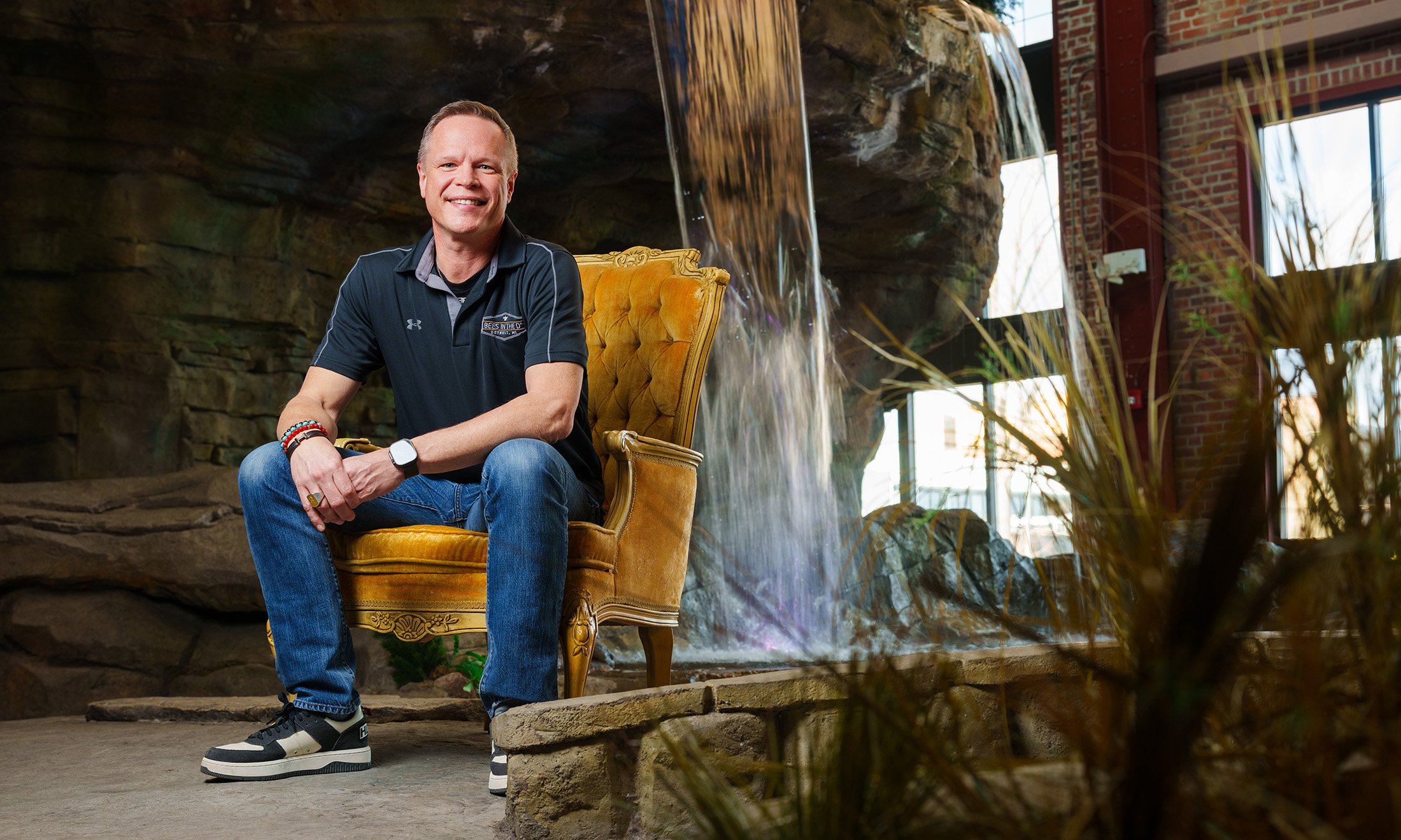 A man sitting in the gold seat in front of a water fountain