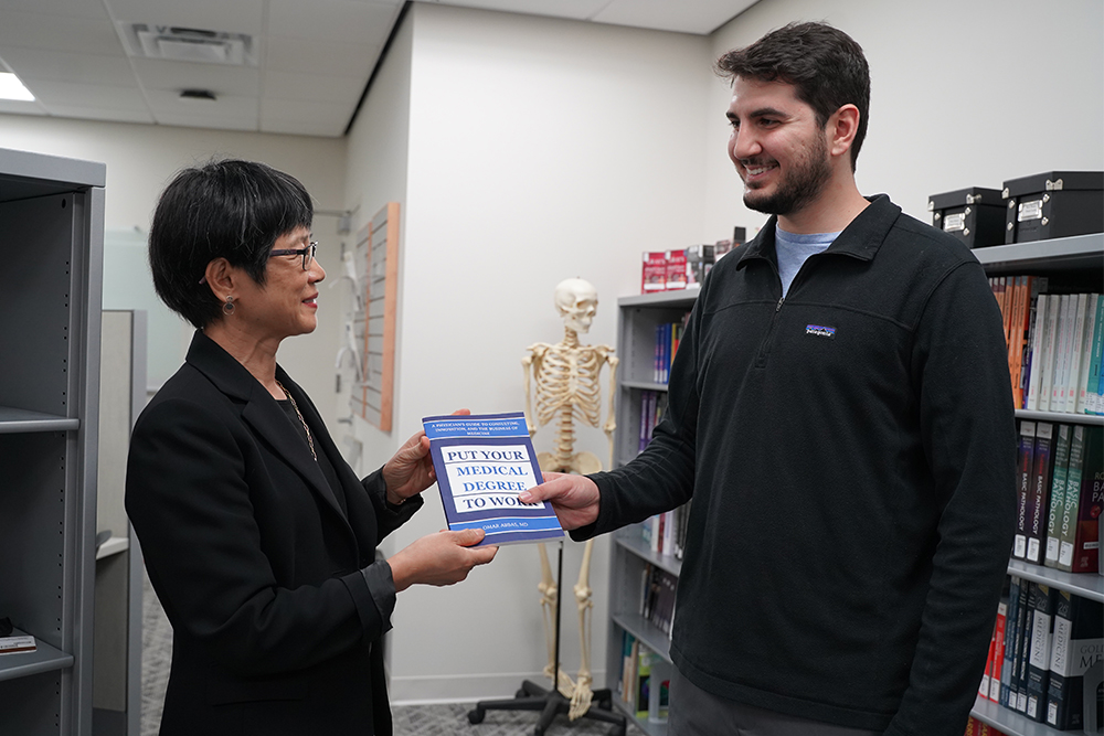 An image of Dr. Abbas handing Dr. Mi a copy of his book