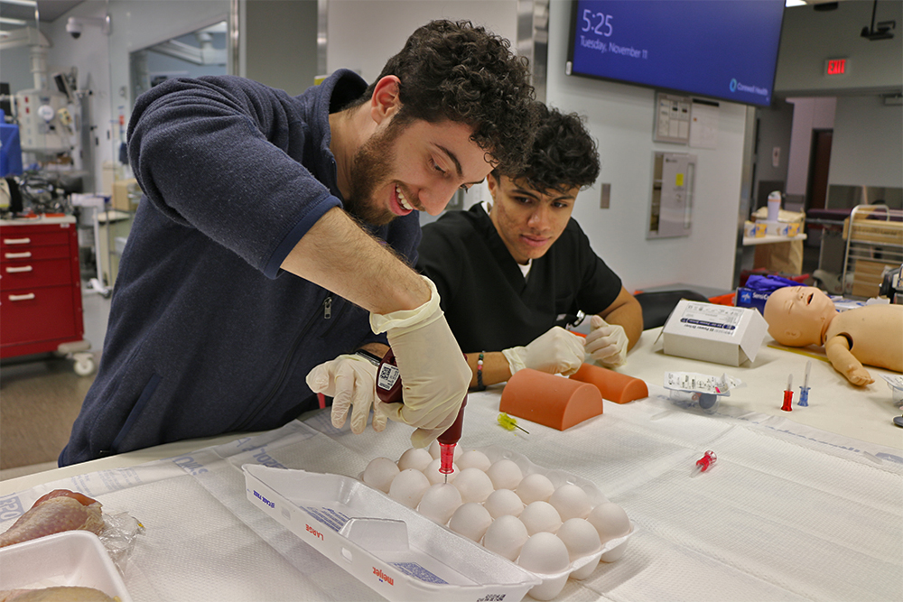 An OUWB student practices a procedure on a chicken egg