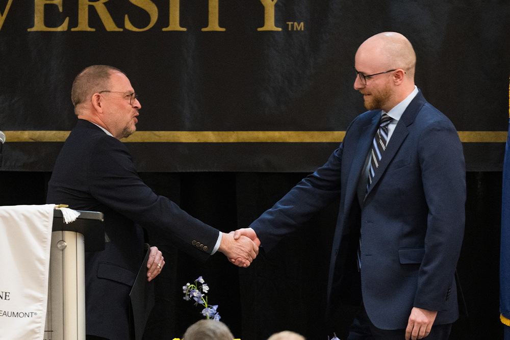 A student is greeted by an OUWB official with a handshake