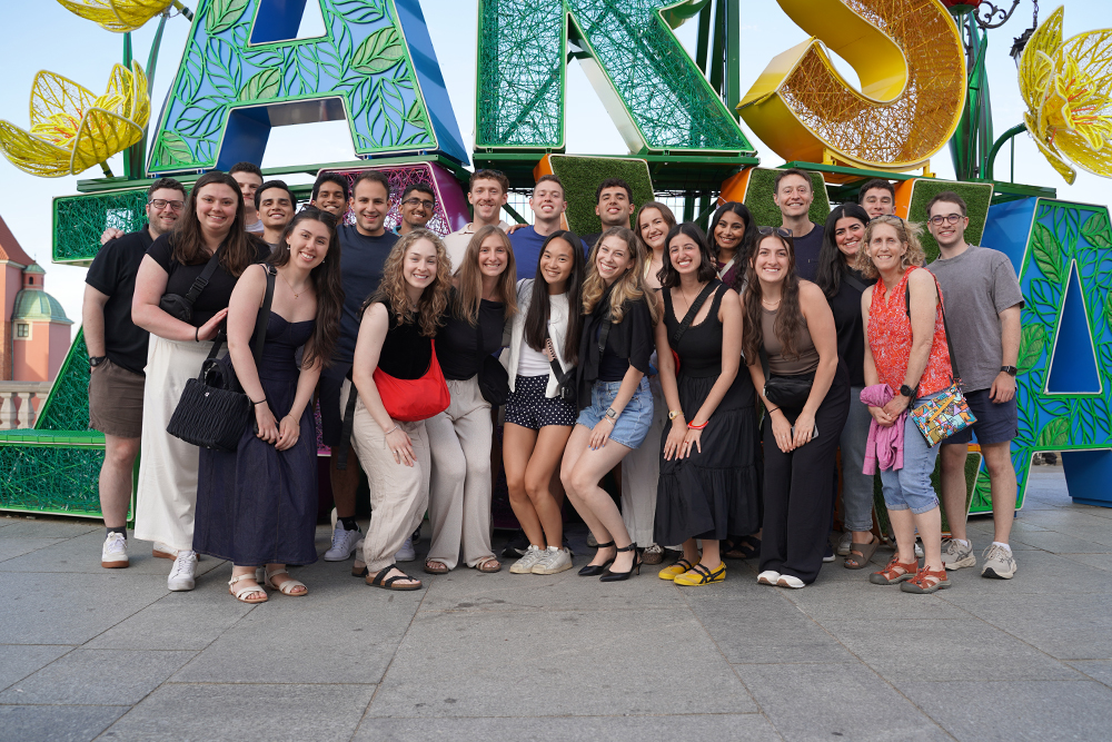 An OUWB cohort stands in front of a sign that reads Warsaw