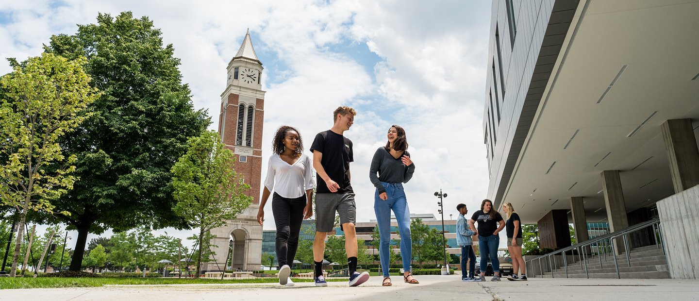 students walking on Oakland University's campus with a clock tower in the background