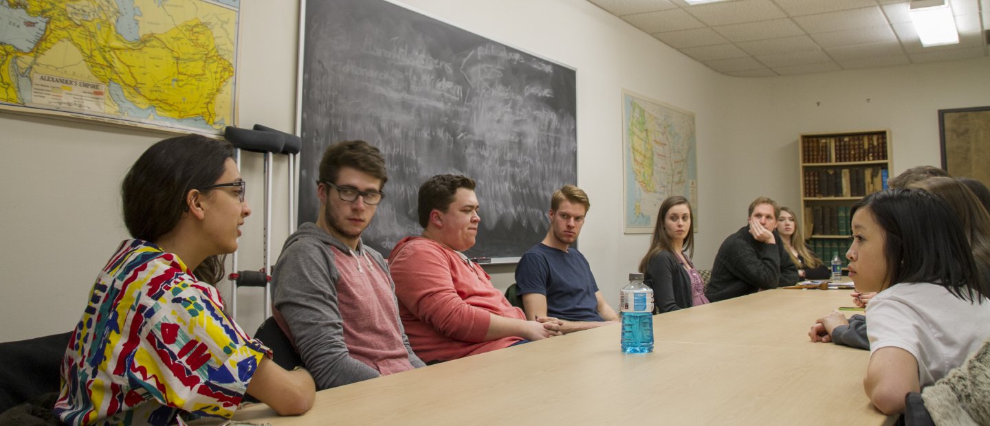 Students seated around a long table, having a discussion.