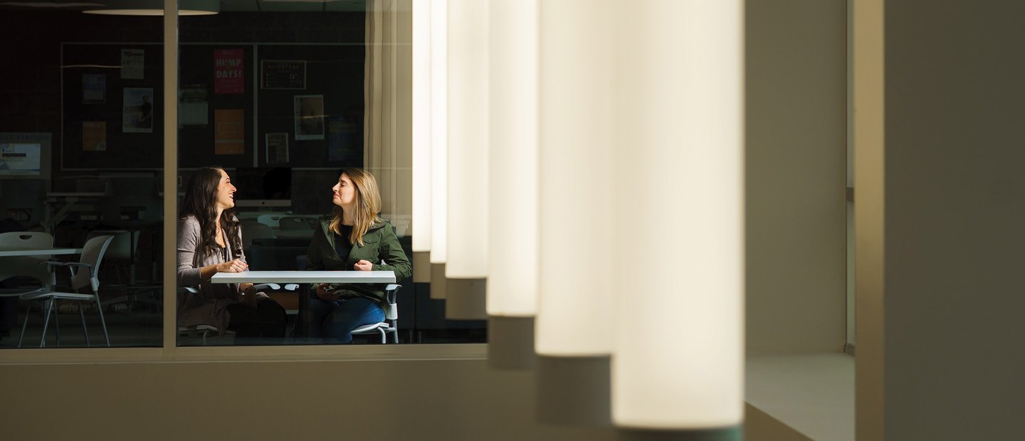 Two young women seated at a table, laughing and talking.