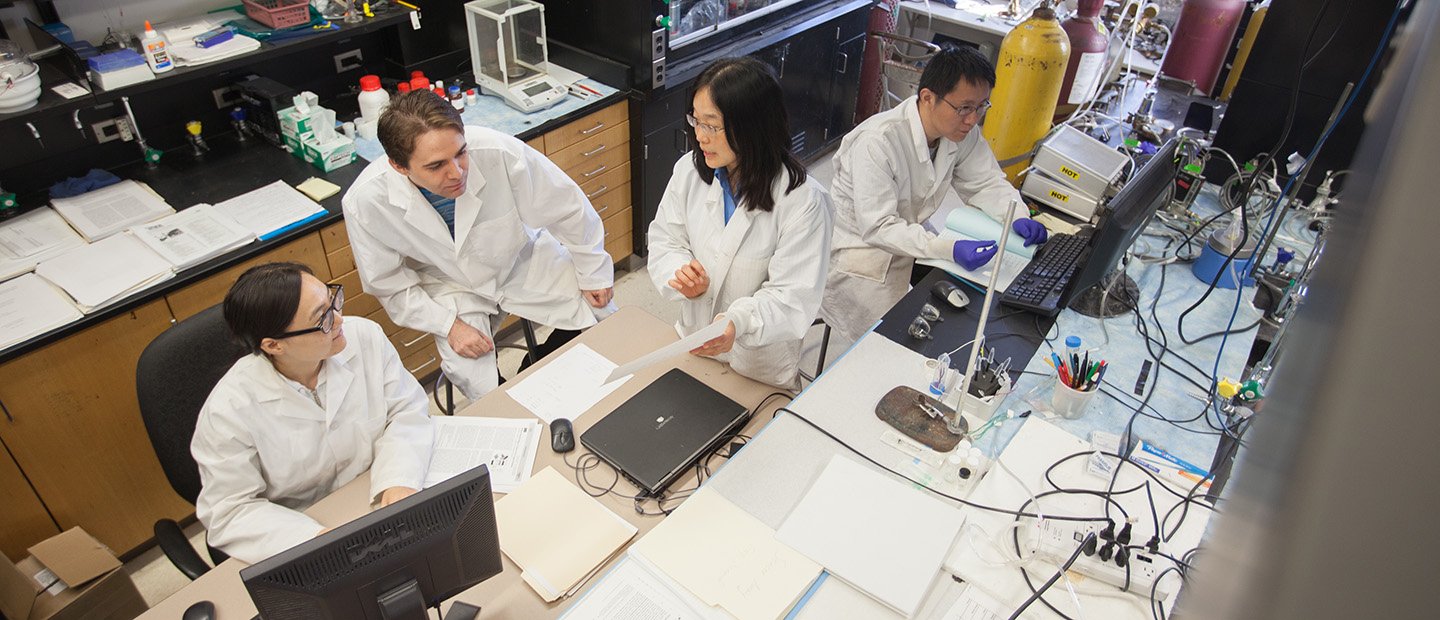 People in white lab coats working in a research lab.