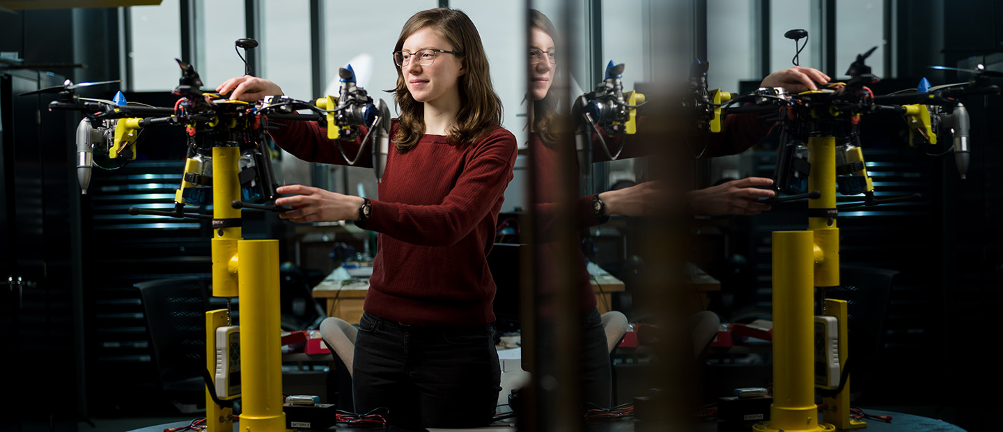 A young woman working with a mechanical device in a lab.