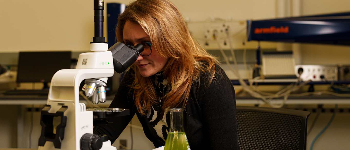 A woman looking into a microscope