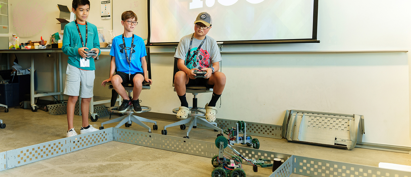 Three young boys using remote controlled robots