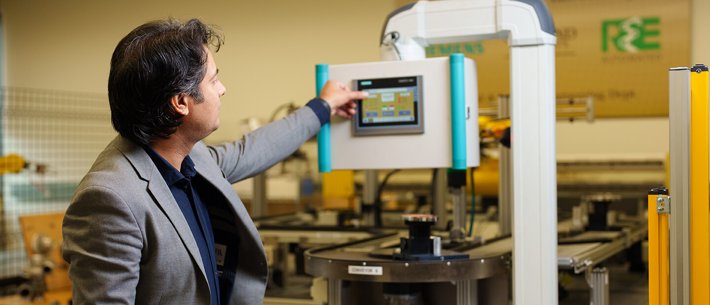 Smart Manufacturing A man works on a touch screen attached to a piece of equipment