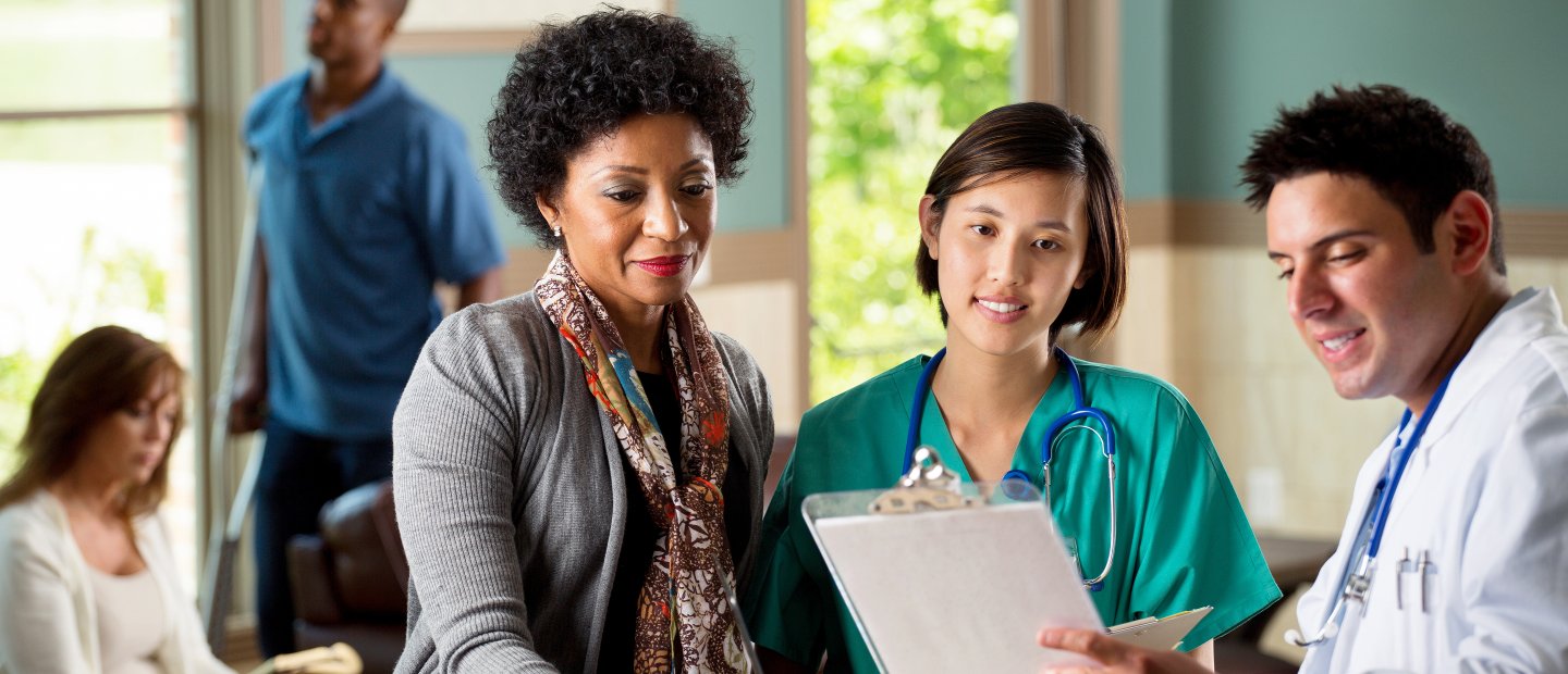 Two doctors and a patient looking at a patient chart.