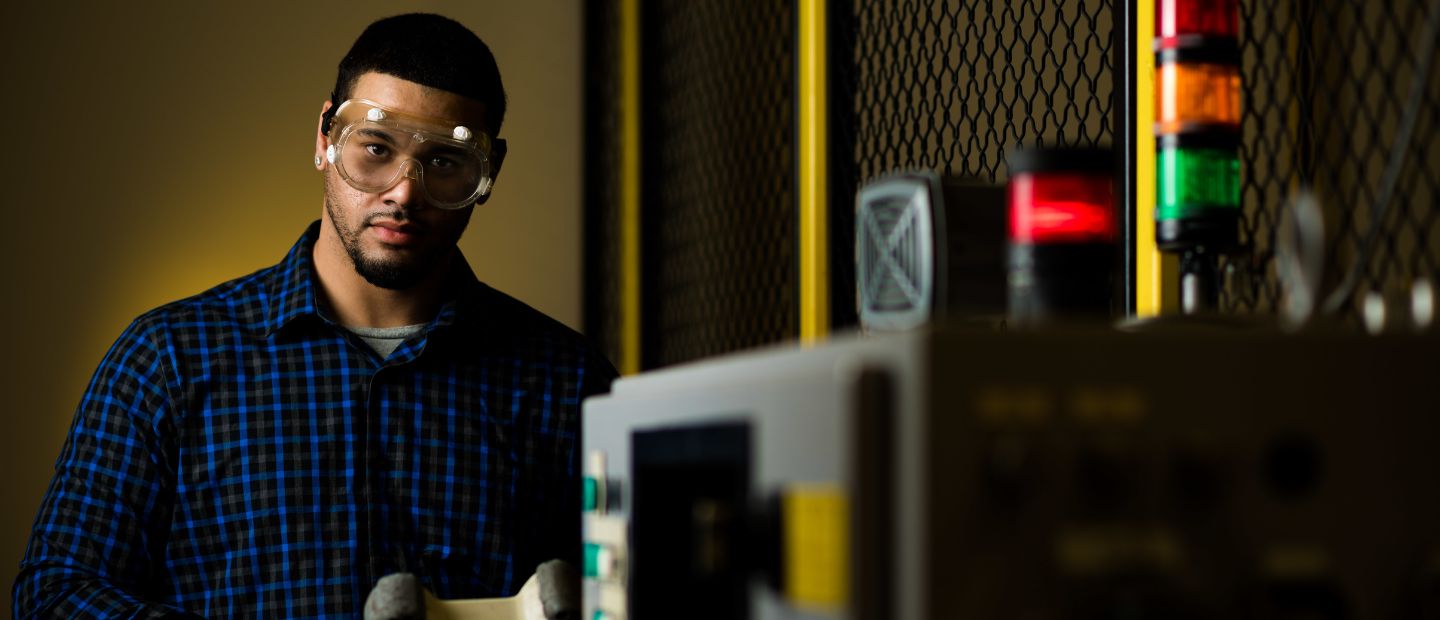 A man wearing safety goggles around mechanical equipment.