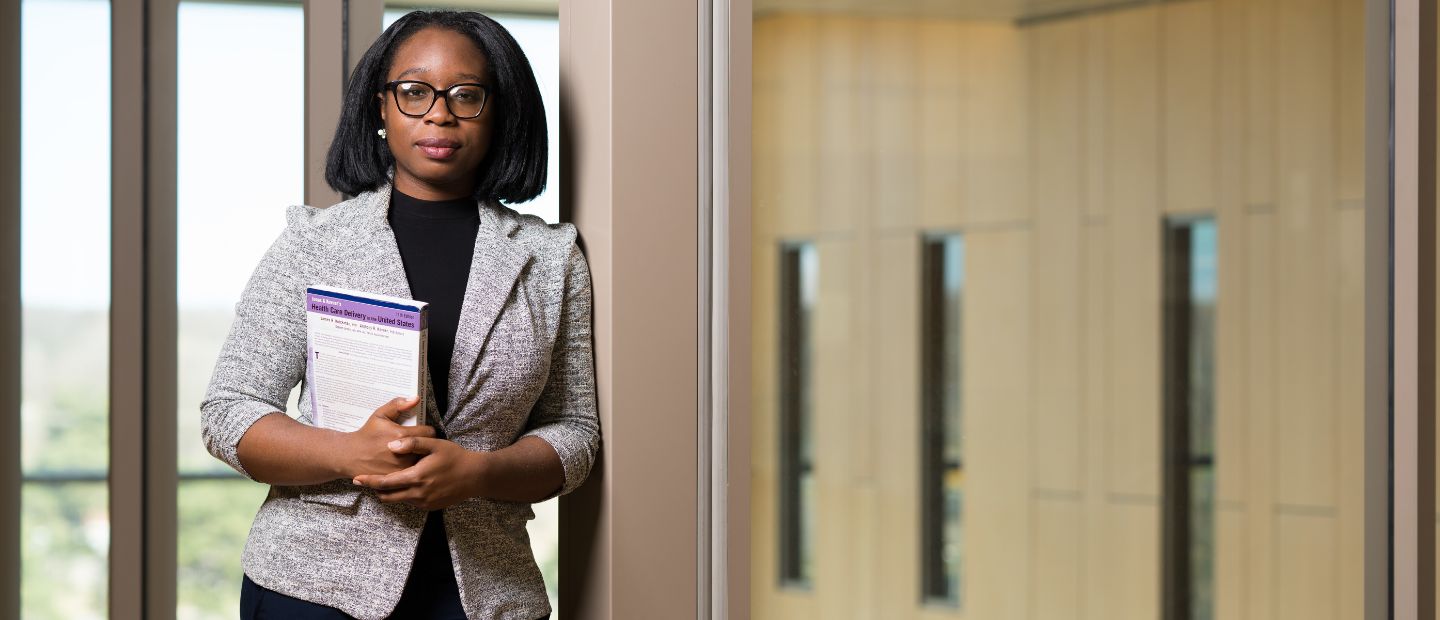 A professional woman holding a notebook, looking at the camera.