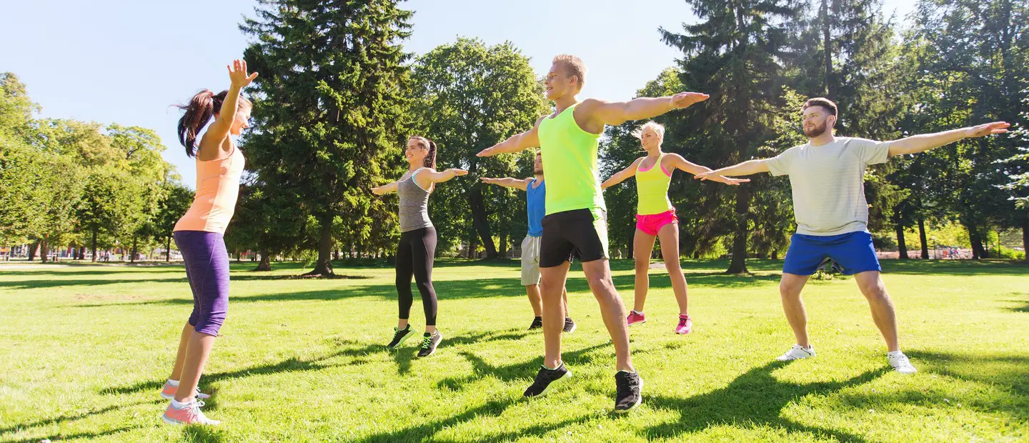 A group of people doing yoga poses outside.