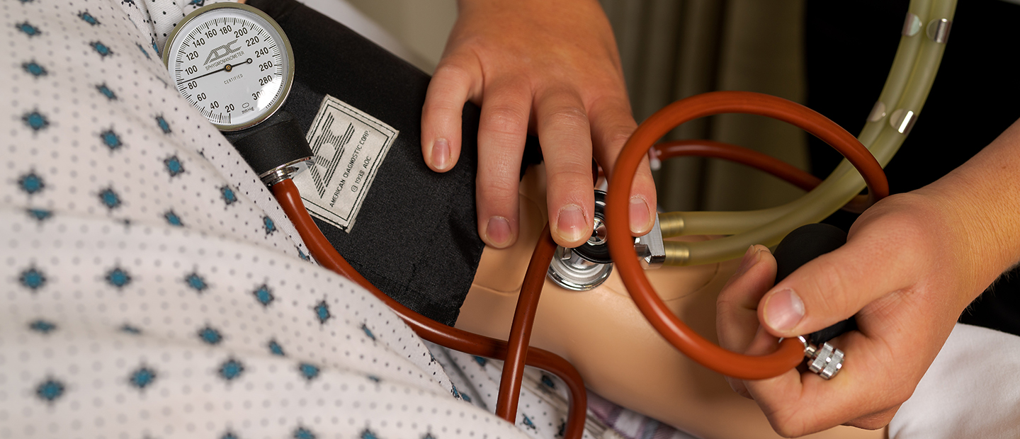 Person testing for blood pressure on a medical dummy