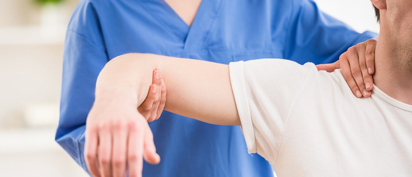 Physical therapist elevating a man's arm to shoulder height