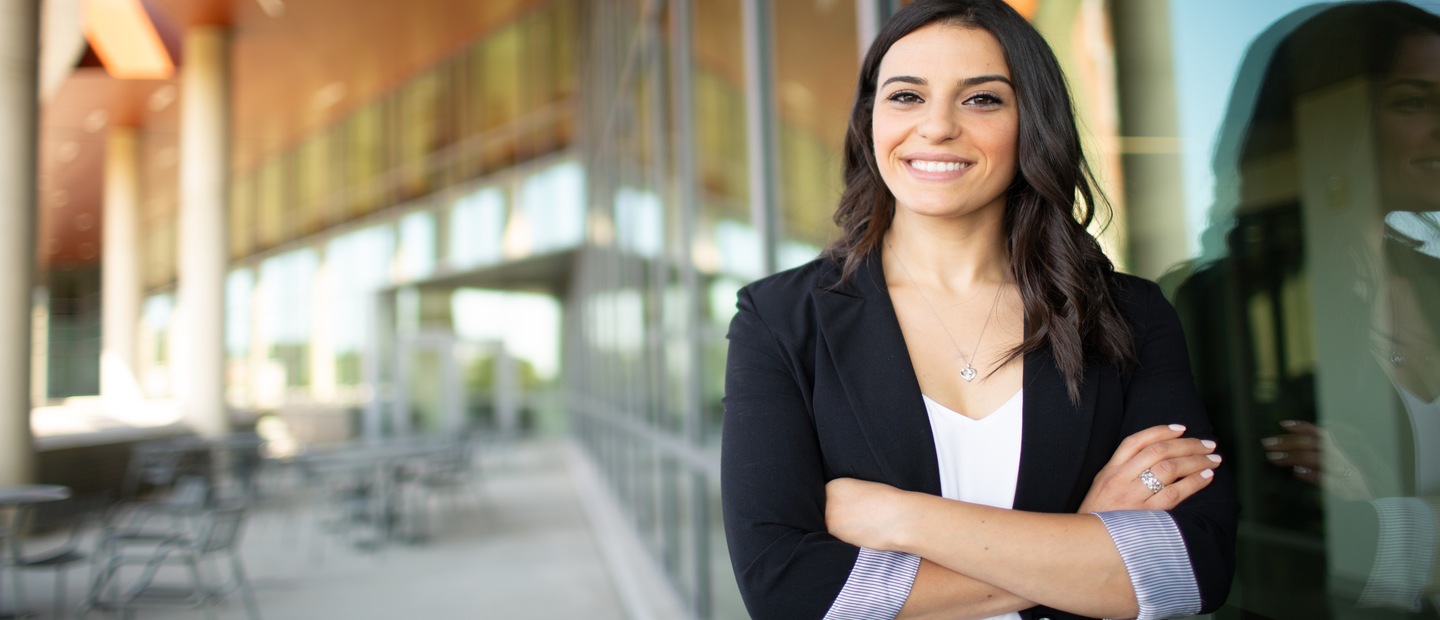 Woman standing and smiling at camera with arms crossed