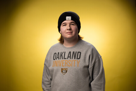 Jameson wearing an O U sweatshirt and beanie looks towards the camera smiling.