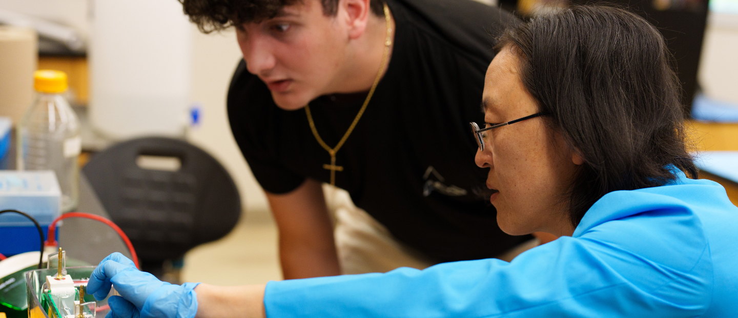 Two people working on a piece of equipment in a classroom