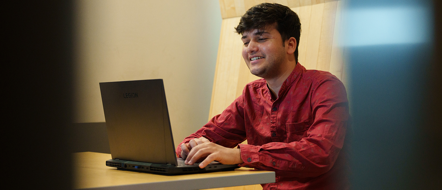 A young man seated, working on a laptop