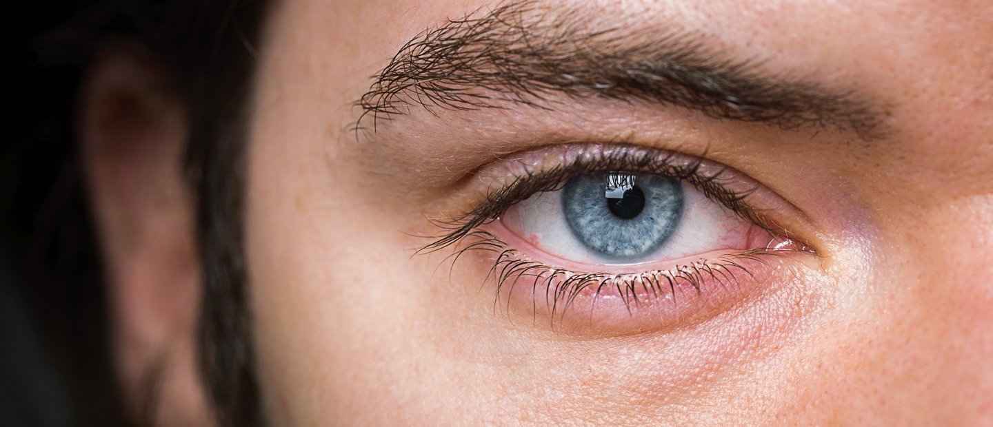 A very close up image of a blue eye with dark eye lashes.