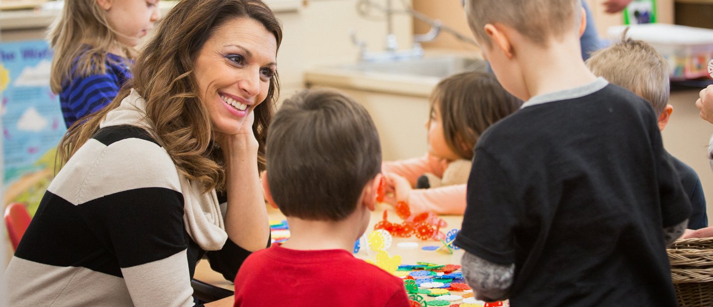 Woman sitting at table with a few kids