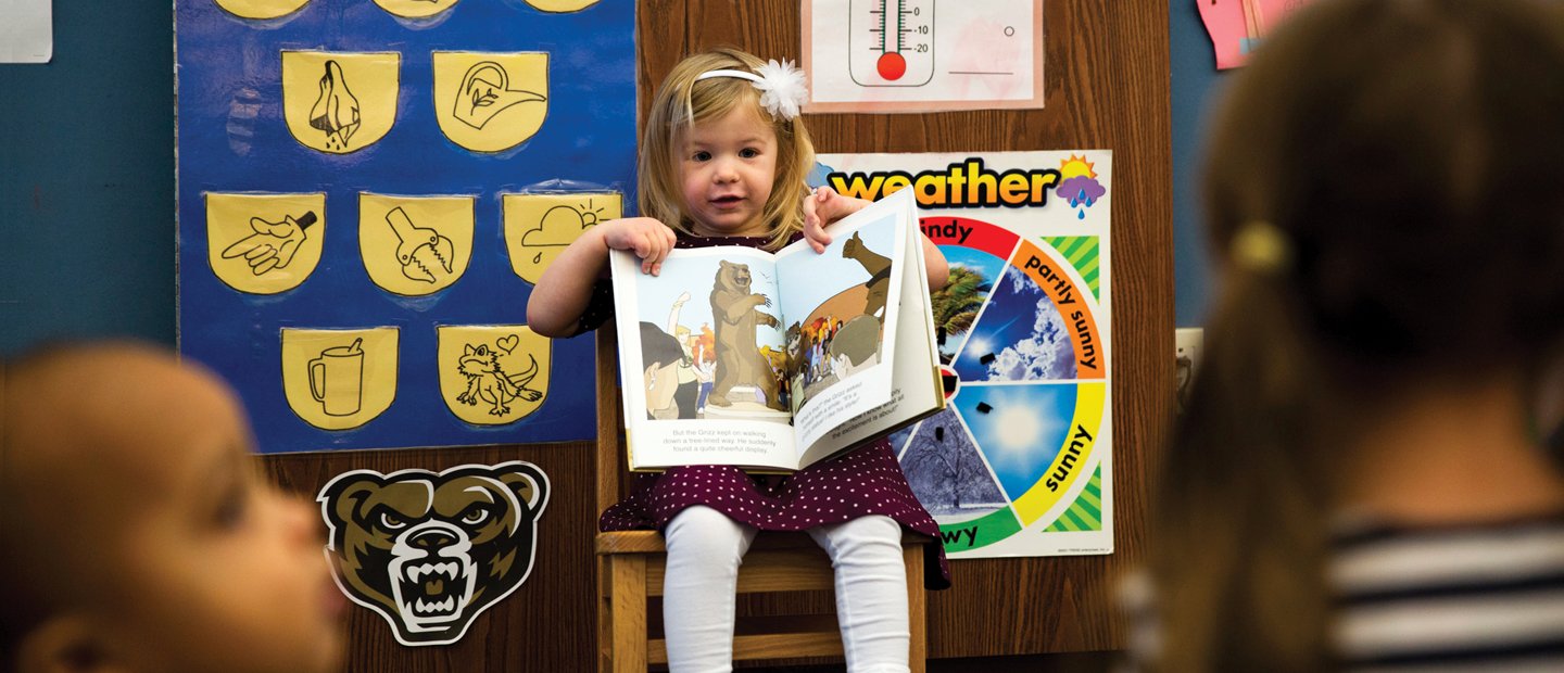 Girl sitting on a chair holding up a book