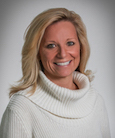 Headshot: Blonde woman in white turtleneck smiling at the camera.