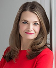 Headshot: Dark haired woman in red top smiling at the camera.